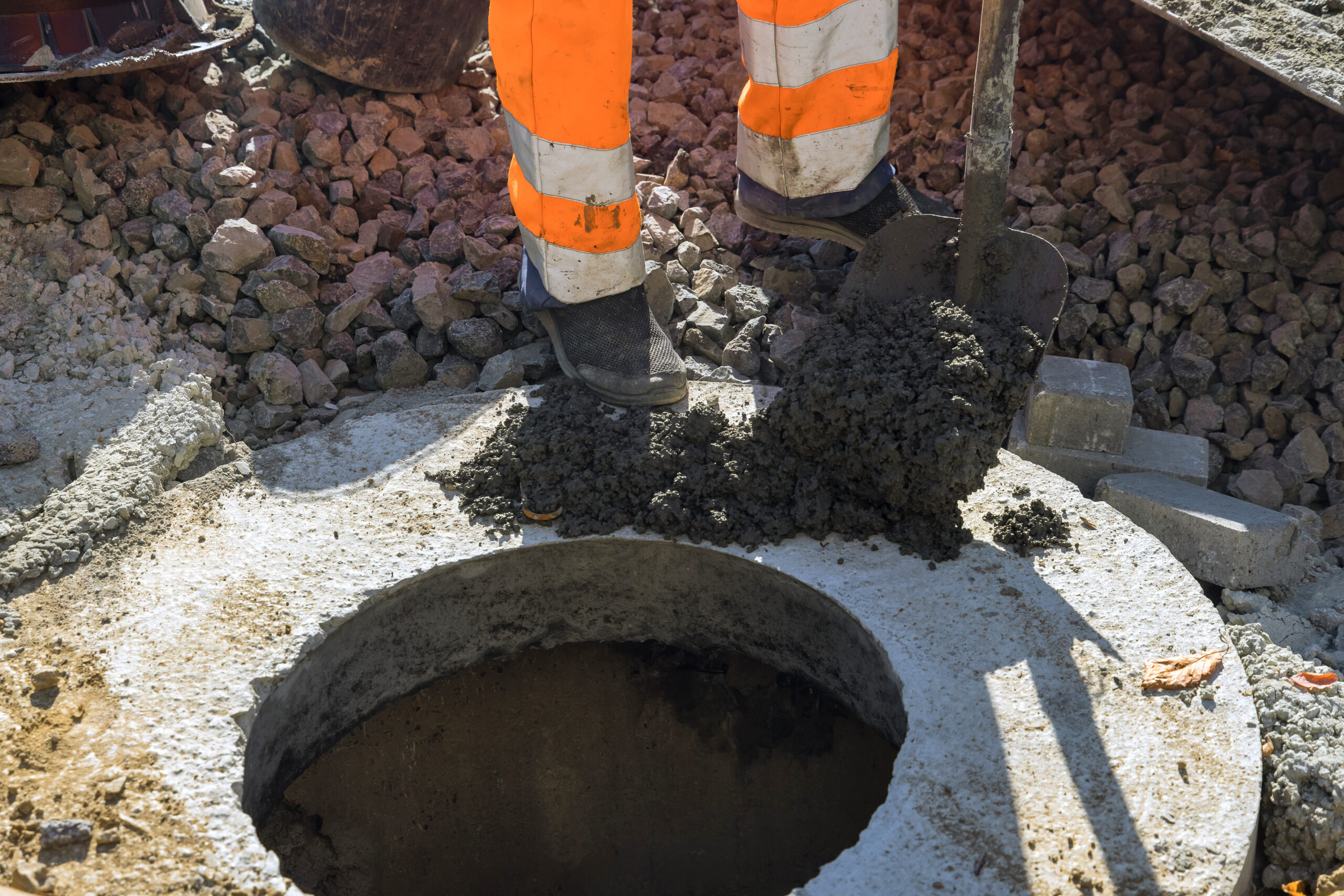A worker the new road construction work on preparation for installation of sewer hatches